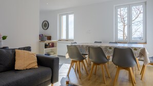 Un salon moderne comprenant un canapé, une table à manger avec des chaises, une bibliothèque et une grande fenêtre.