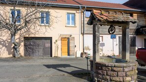 Un bâtiment avec un puits en pierre, une porte en bois et un panier de basket.