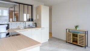 Une cuisine moderne avec des meubles blancs, une cuisinière encastrée et une machine à café.