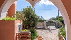 A courtyard with a stone bench, a gate, and a cactus plant. - Villa 'Morgana' with Private Terrace, Wi-Fi and Air Conditioning (Fontane Bianche)
