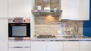A modern kitchen with stainless steel appliances, a built-in oven, a gas stove, and a backsplash with a herringbone pattern. - Villa 'Morgana' with Private Terrace, Wi-Fi and Air Conditioning (Fontane Bianche)