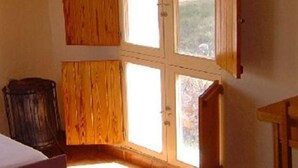A room with a bed, wooden walls, a window, and a door.