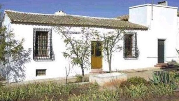 A white building with a tiled roof, a small porch, and a single door.