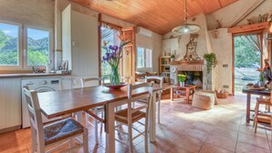 A spacious kitchen with wooden cabinets, a dining area with a large table and chairs, and a view of the mountains through the windows. - Country House 'El Castellet De L'Ocaive' with Mountain View, Wi-Fi and Air Conditioning (Alicante)