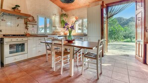 A kitchen with white cabinets, a wooden ceiling, and a dining area with a table and chairs. - Country House 'El Castellet De L'Ocaive' with Mountain View, Wi-Fi and Air Conditioning (Alicante)