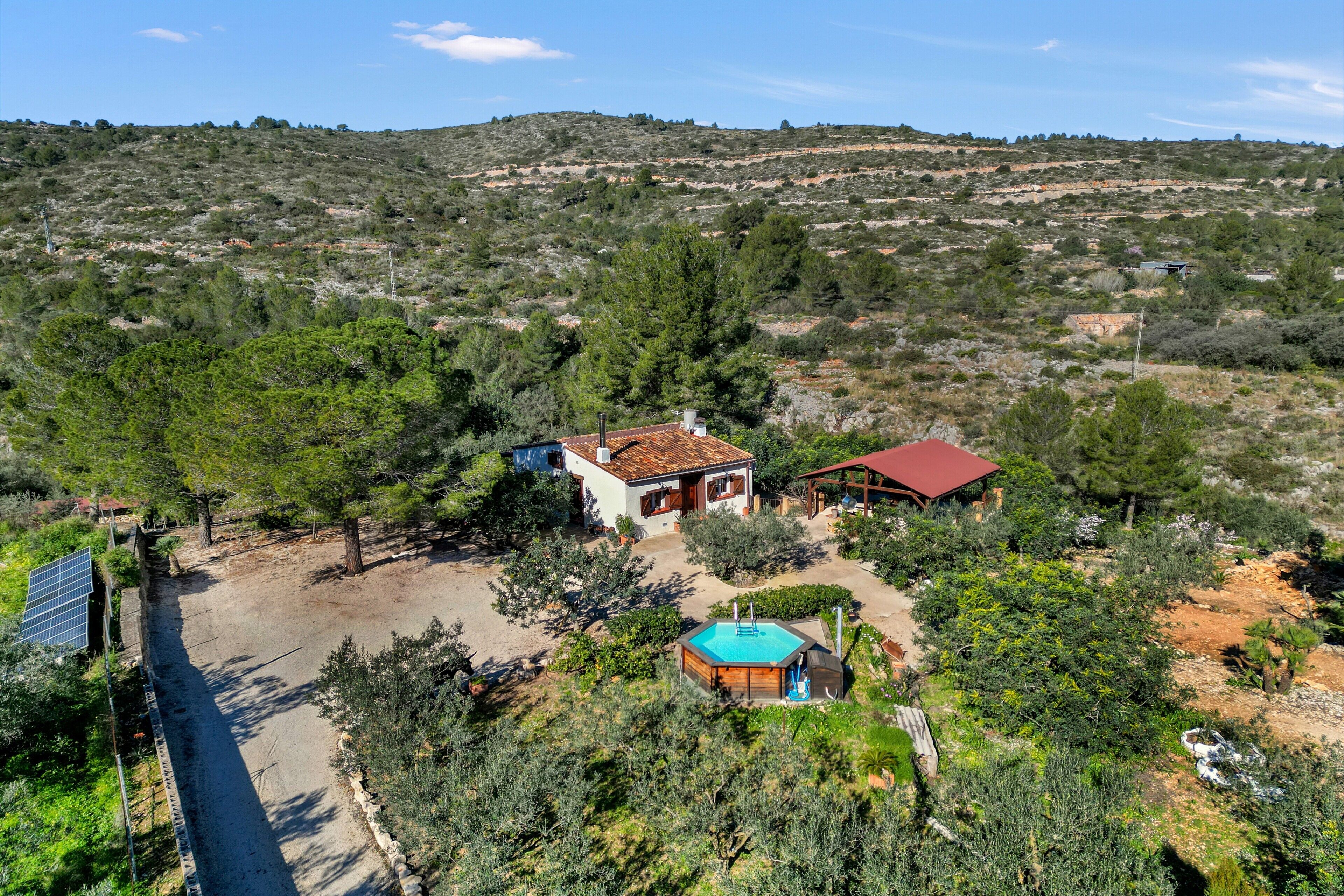 A rural property with a swimming pool, a red-roofed building, and a white building with a tiled roof.