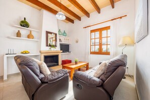 Una sala de estar con dos sofás de cuero, una mesa de madera, una chimenea y un televisor.
