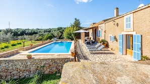A stone pool with lounge chairs, a stone wall, and a building with blue shutters. - Villa 'Pascual Gran' with Mountain View, Private Pool and Wi-Fi (Manacor)