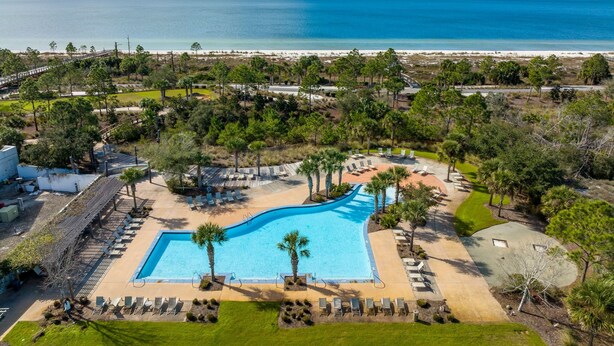 Vue aérienne d’un complexe hôtelier doté d’une grande piscine, d’espaces de détente et offrant une vue sur la plage.