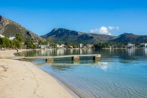 A beach with clear water, a wooden pier, and mountains in the background. - Apartment 'Faro Attic B' with Sea View, Wi-Fi and Air Conditioning (Pollença)