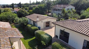 A residential area with a white building, a paved courtyard, and surrounding greenery.