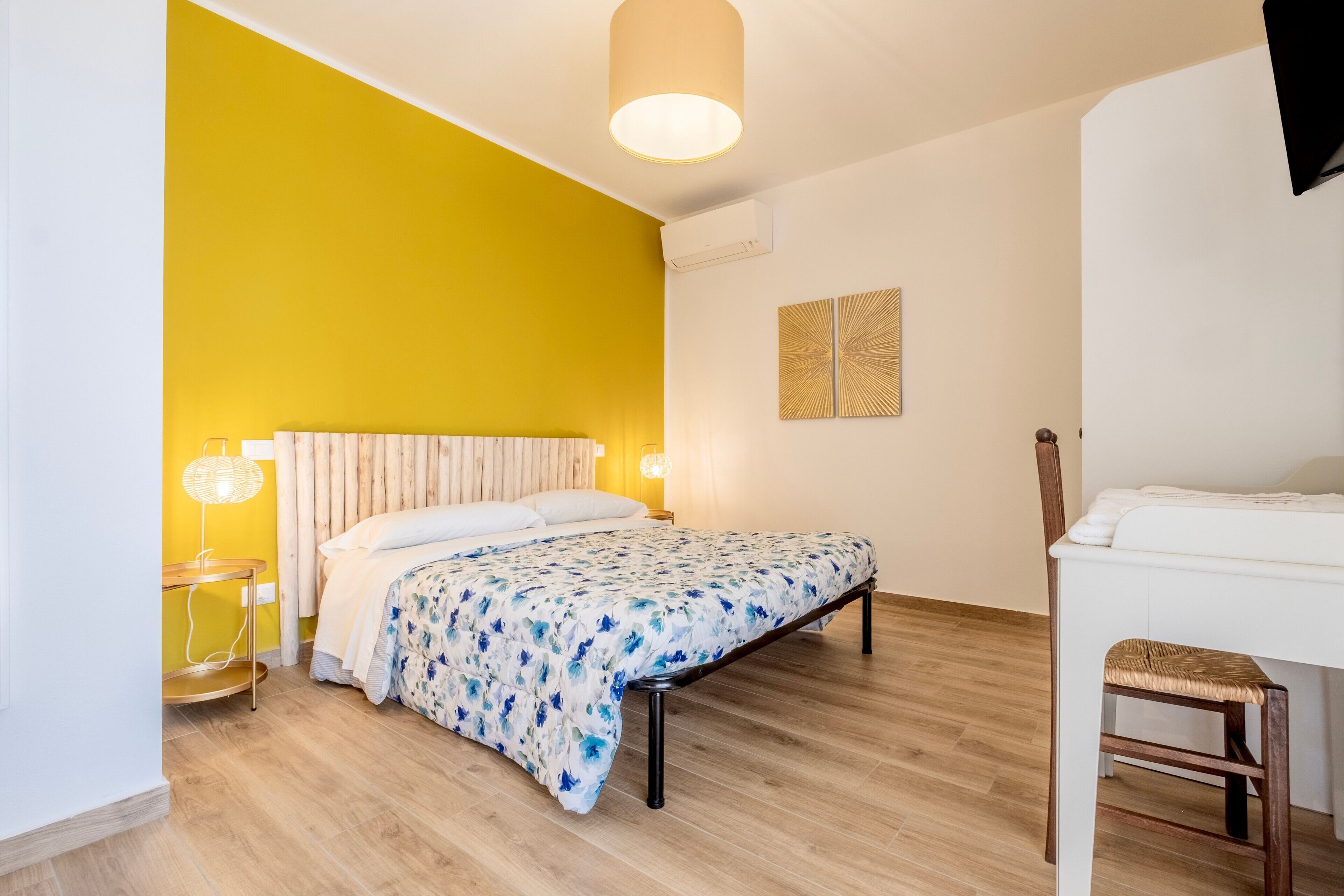 A bedroom with a bed, bedside table, lamp, and a chair.