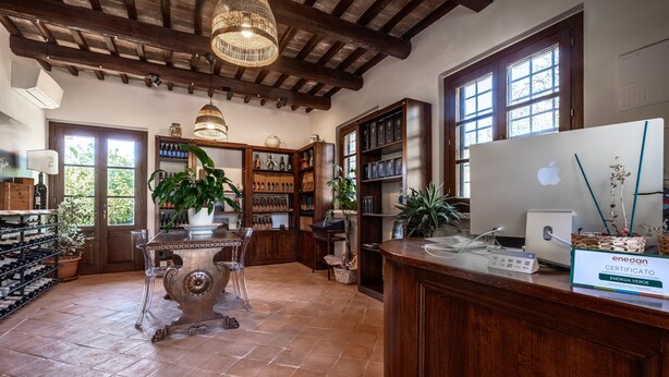 A spacious room with a wooden ceiling, a large desk with a computer, shelves with bottles, and a wine rack. - Apartment 'Pendolino' with Shared Pool, Wi-Fi and Air Conditioning (Capalbio)