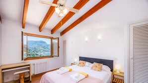 A bedroom with a large bed, a desk, a chair, a window with a view, and a ceiling fan. - Apartment 'Sa Torreta Luxury Views' with Sea View, Private Terrace and Wi-Fi (Sóller)