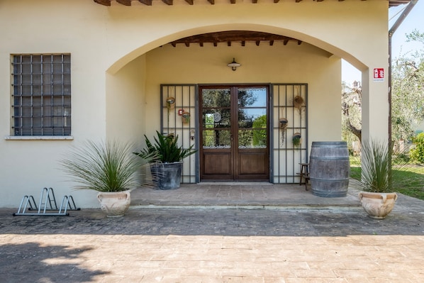 A building entrance with a wooden door, potted plants, and a metal gate.
