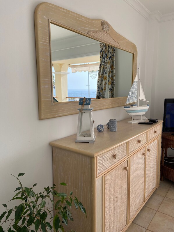 Una habitación con un espejo grande, un modelo de velero, un farol y una planta.