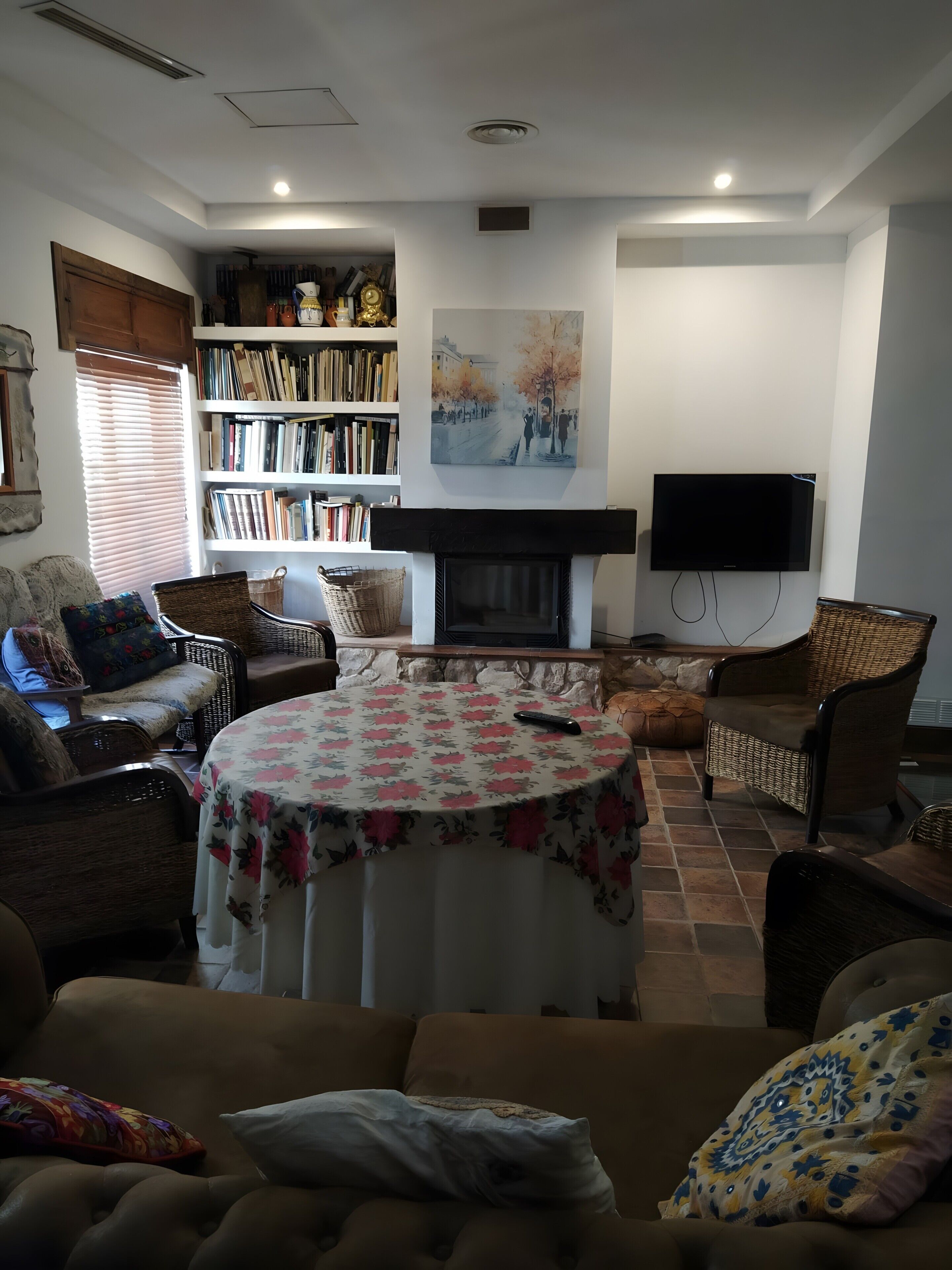 Una sala de estar con chimenea, televisor, estantería y una mesa redonda.
