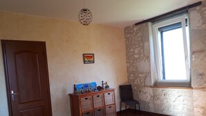 Een slaapkamer met een bed, een dressoir met manden, een stoel, een deur en een raam.