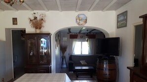 Een woonkamer met een televisie, een bank, een houten kast en een grote vaten.