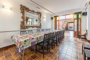 A dining area with a long table, chairs, a mirror, and a view into another room.
