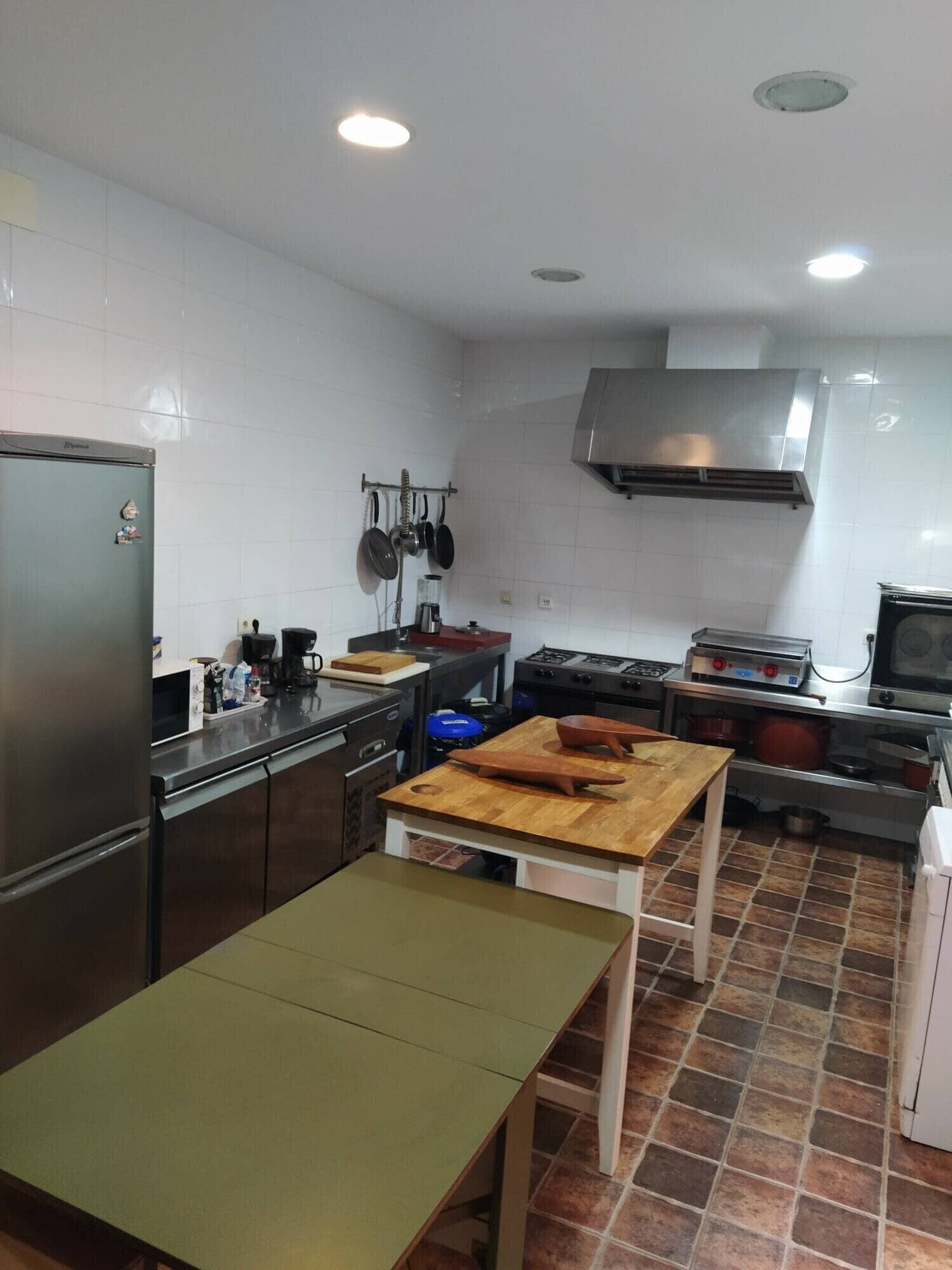 A kitchen with a refrigerator, stove, oven, and a wooden table.