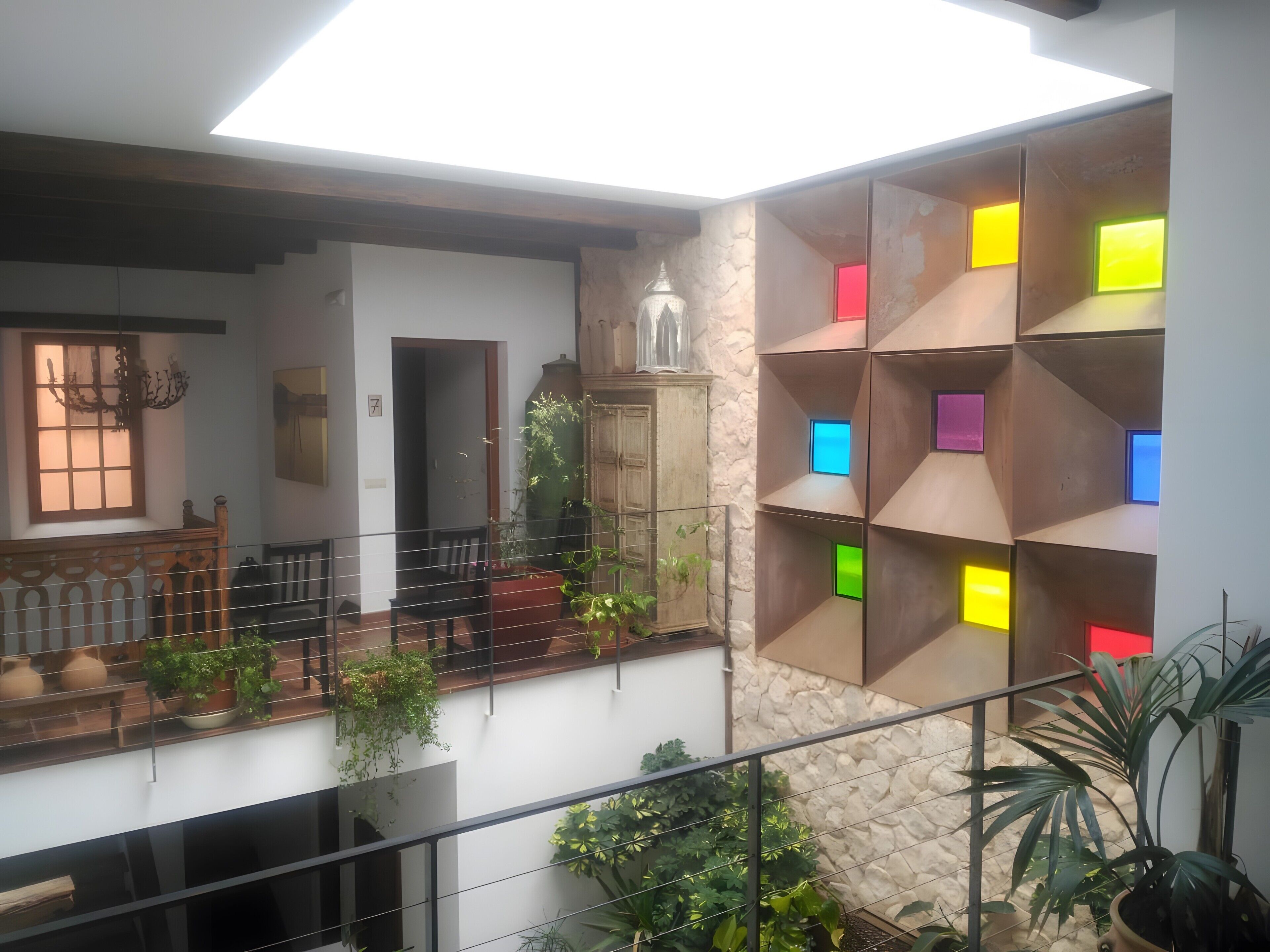 A multi-level interior with a staircase, potted plants, and a wall with illuminated panels.