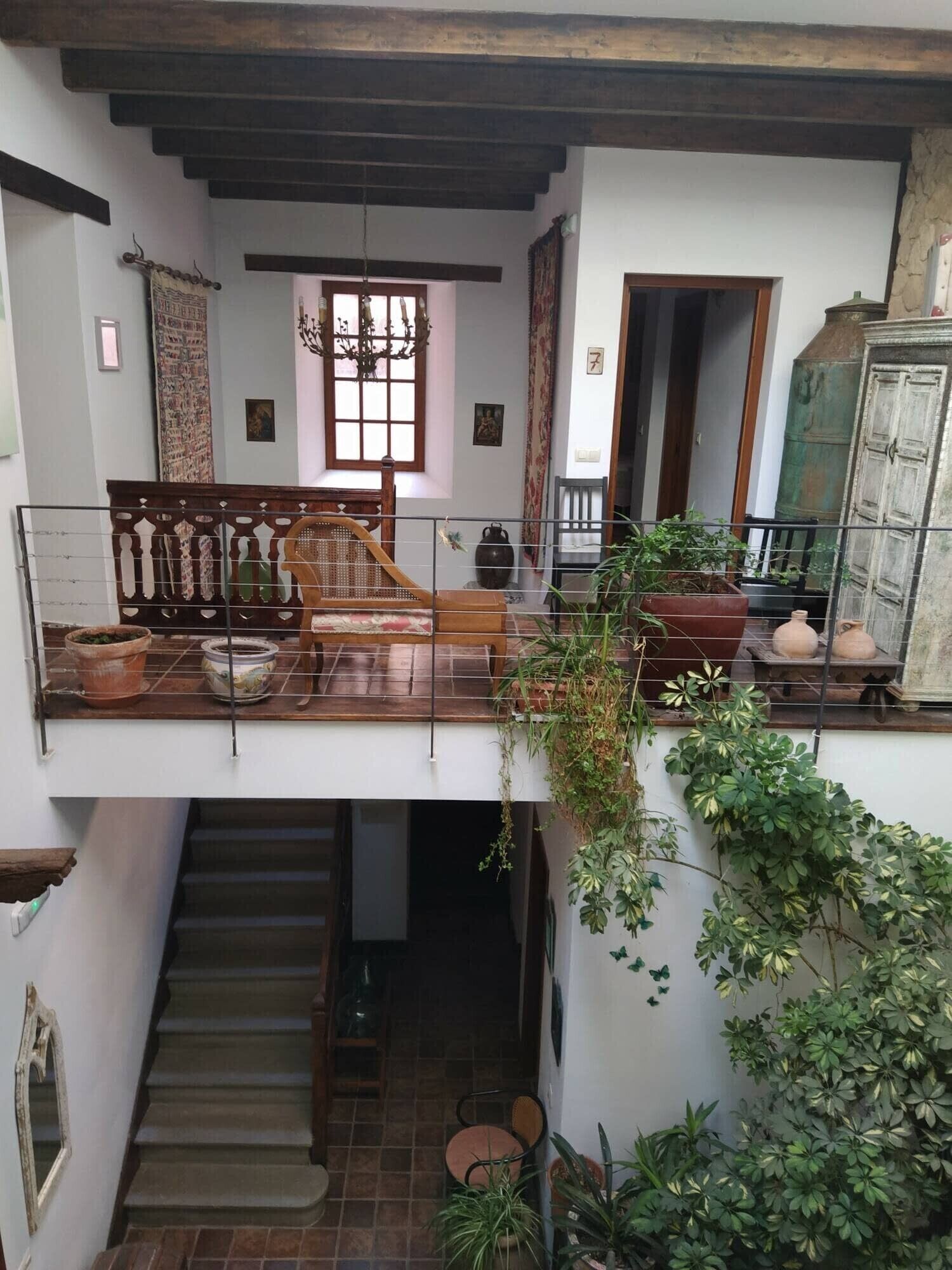 Ein mehrgeschossiges Interieur mit einer Treppe, Holzmöbeln und Topfpflanzen.