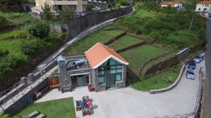 Ein modernes Haus mit Natursteinfassade, rotem Dach und befestigter Auffahrt.