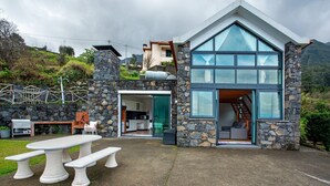 Ein modernes Haus mit Steinfassade, einem großzügigen Essbereich mit Bänken und einer sichtbaren Küche.