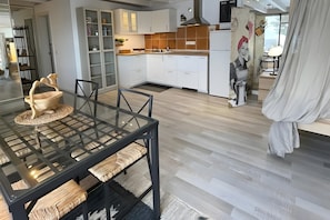 Une cuisine moderne avec des armoires blanches, un plan de travail en bois et une fresque murale.