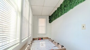 A room with a wooden table, white walls, and a green wall decoration. - Spacious 3BDR near Harvard/5-Min Walk to Train - Davis Sq / Free Parking! (Somerville)