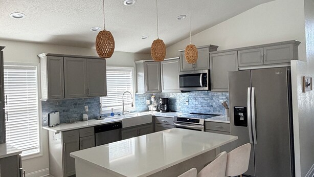 A modern kitchen with a large island, stainless steel appliances, and pendant lighting. - PROMO August 20% off! 5 bed/3bath/private pool-Disney/Universal (Clermont)