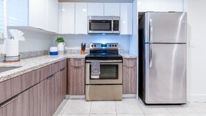 A modern kitchen with white cabinets, stainless steel appliances, and a granite countertop.