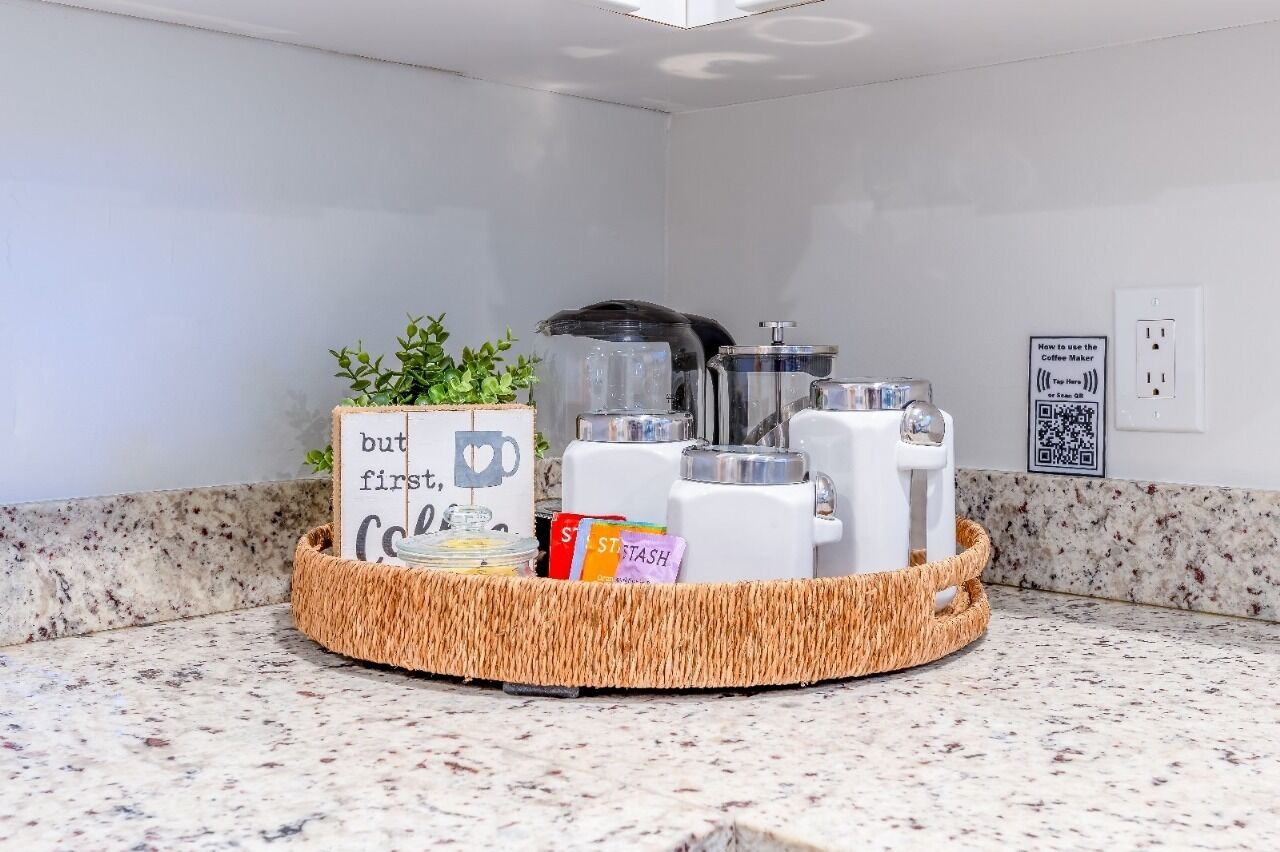 A kitchen counter with a coffee maker, a basket with a sign, and a QR code on the wall.