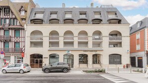 A building with a modern facade, a ground-floor entrance labeled "CREDIT AGRICOLE," and a car parked in front. - Modern Apartment with Terrace Trouville (Trouville-sur-Mer)