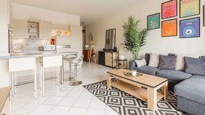A modern living room with a grey sofa, a wooden coffee table, and a kitchen area with white cabinets and a marble countertop. - Modern Apartment with Terrace Trouville (Trouville-sur-Mer)