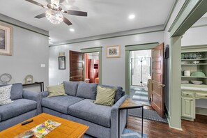 A living room with a grey sofa, a wooden coffee table, and a ceiling fan. - Cottage near the New Orleans Airport (Destrehan)