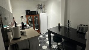 A compact kitchen with a black countertop, a white refrigerator, a microwave, and a toaster. - Seaside Stay Sleeps 6 With Pets (Great Yarmouth)