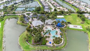 An aerial view of a resort with a central swimming pool, tennis courts, and a golf course. - Sandy Bottoms - Resort Style Community Ammenities, Sandy Bottoms! (Cape Coral)