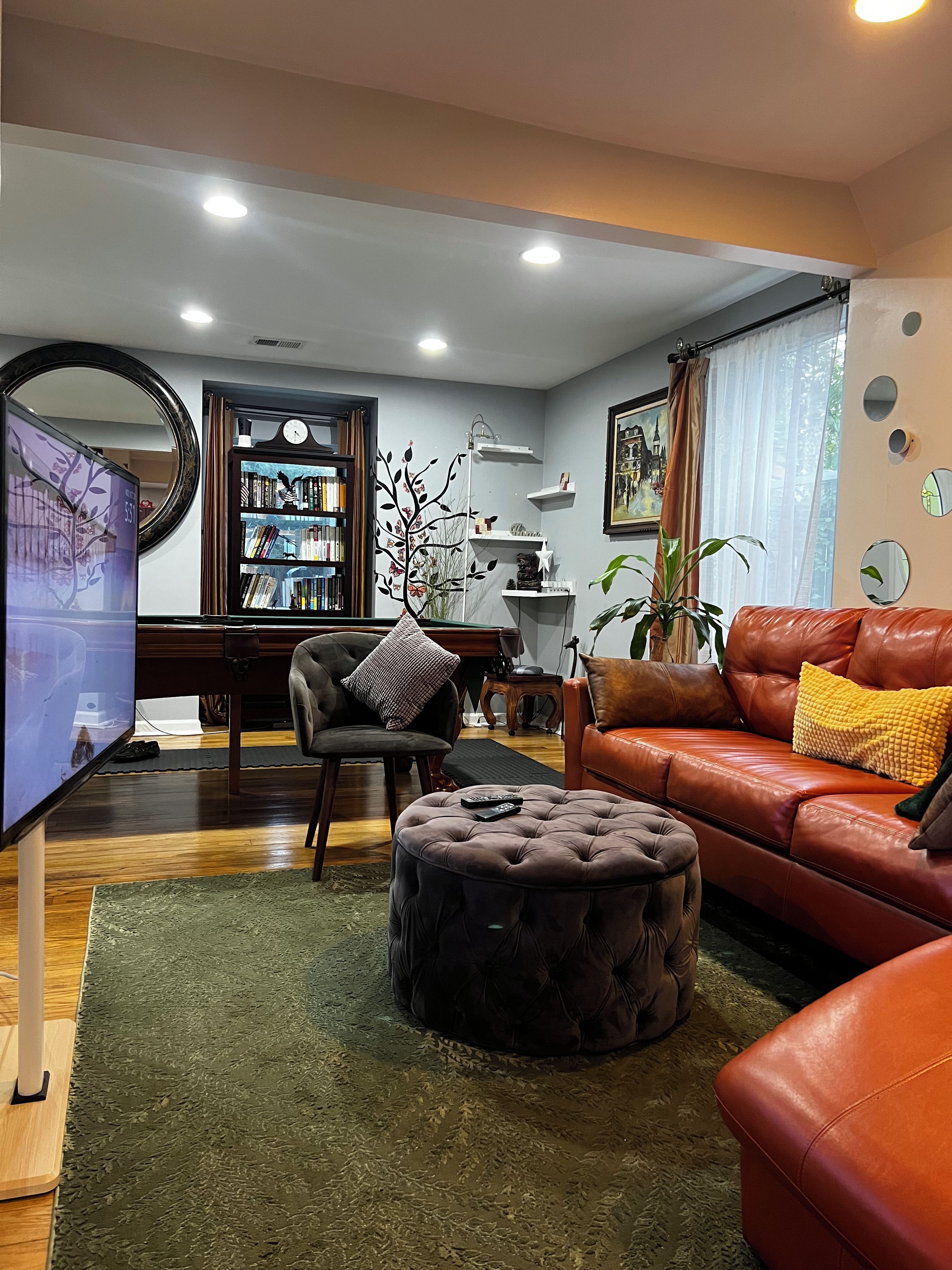 A living room with a leather sofa, ottoman, and a bookshelf.