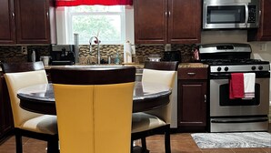 A kitchen with a dining table, chairs, a microwave, a stove, and cabinets.