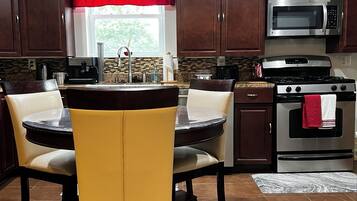 A kitchen with a dining table, chairs, a microwave, a stove, and cabinets.