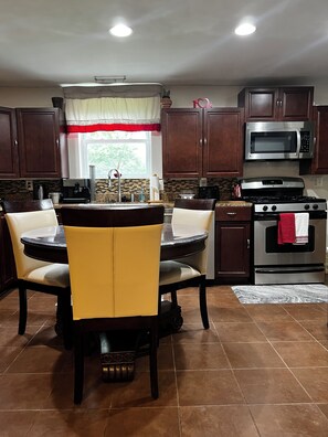 A kitchen with a dining table, chairs, a microwave, a stove, and cabinets.