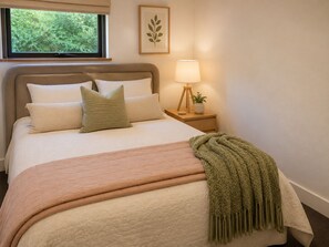 A neatly made bed with pillows and a blanket, a bedside lamp, and a framed plant on a nightstand. - Stunning Modern Accommodation on Prestige Rural Property (Richmond Lowlands)