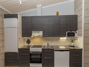 Une cuisine moderne avec des meubles de couleur bois foncé, un réfrigérateur blanc, un four à micro-ondes, une cuisinière et un lave-vaisselle.