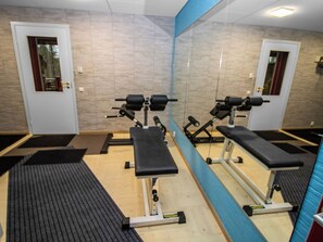 Une salle de sport équipée de matériel d’exercice, d’un miroir et d’une porte.