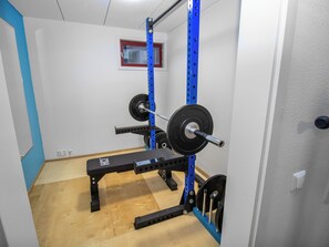Un espace dédié à l’haltérophilie, équipé d’un banc, d’une barre et de disques de poids.