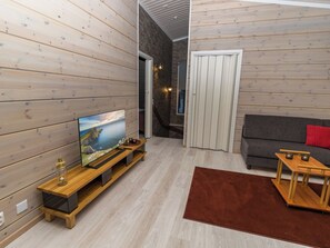 A modern living room with a flat-screen TV on a wooden stand, a gray sofa, and a brown rug.