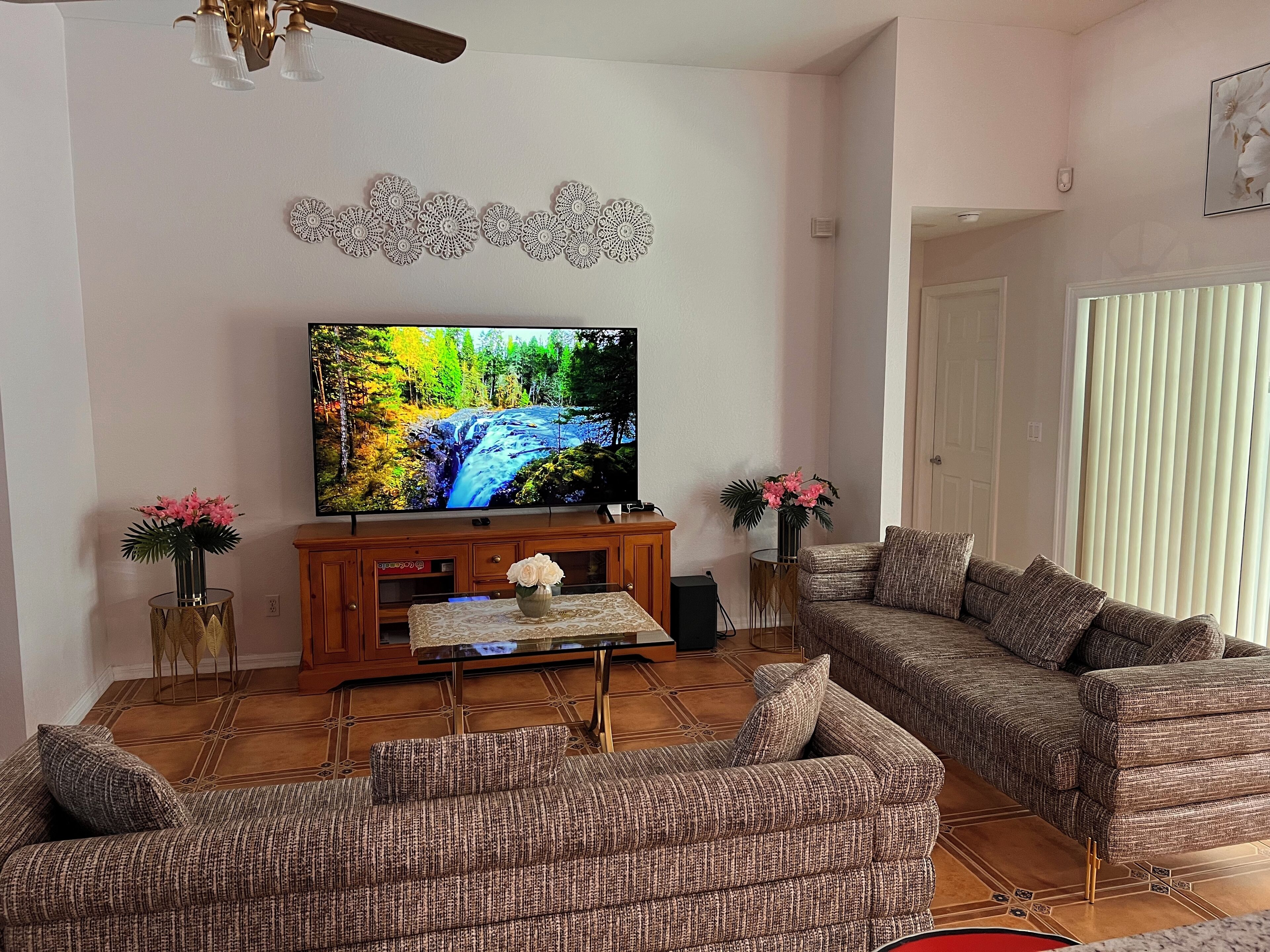 A living room with a large flat-screen TV, two sofas, a coffee table, and decorative vases.