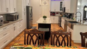 Una cucina moderna con mobili bianchi, un'isola centrale e un'area pranzo con un tappeto decorato.